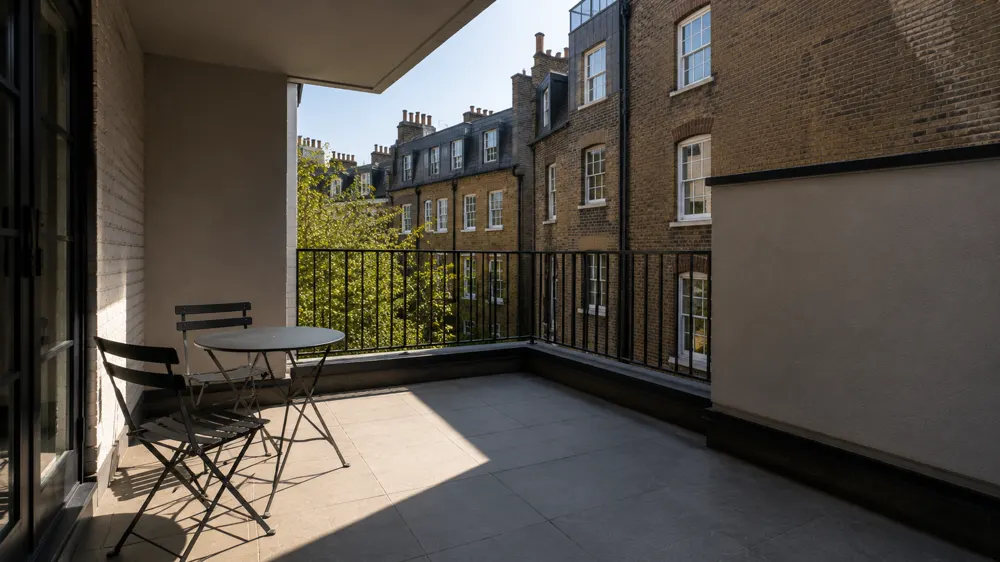 Wide scene: a balcony in morning light, half in sun and half in shade